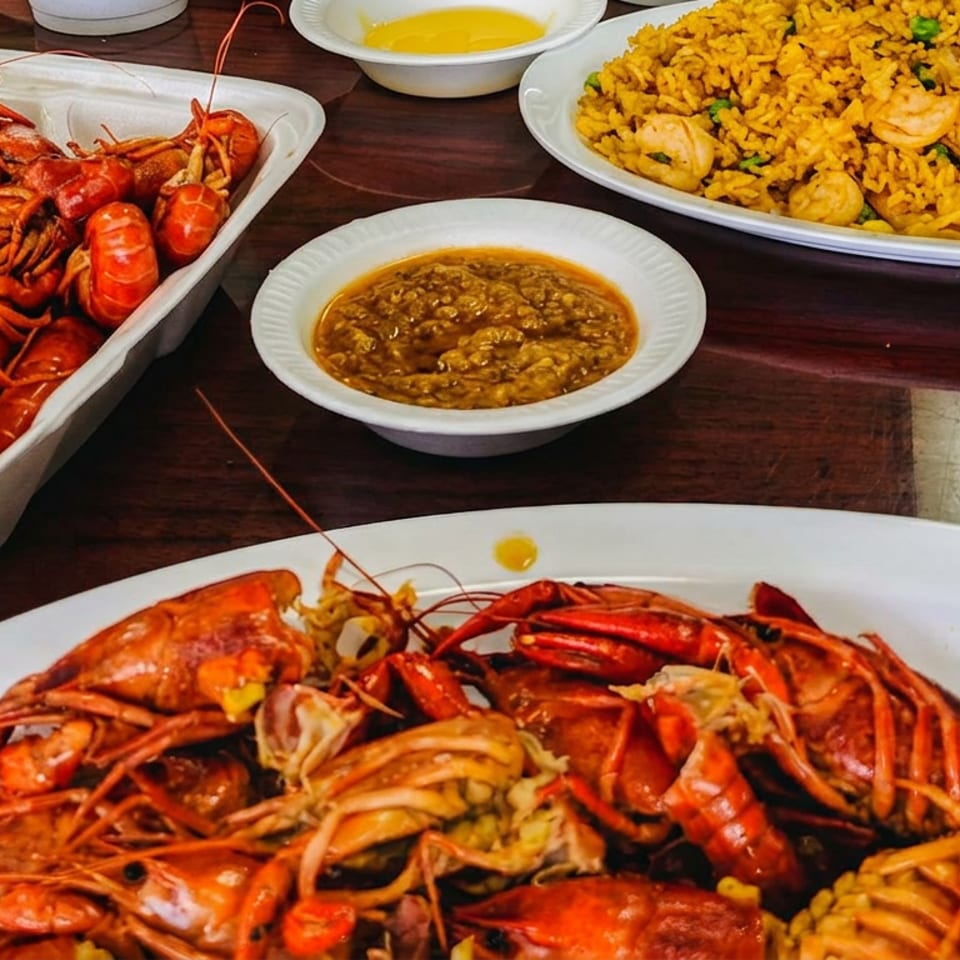Boiled crawfish, shrimp fried rice, and dipping sauces on a dark wooden table.
